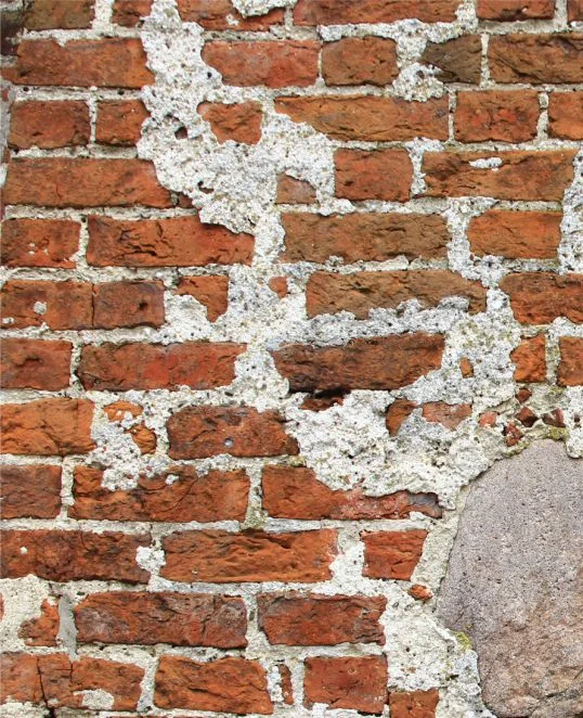 Alte Backsteinmauer mit sichtbaren Ausbesserungen und Patina, ideal zur Veranschaulichung von Sanierungstechniken.