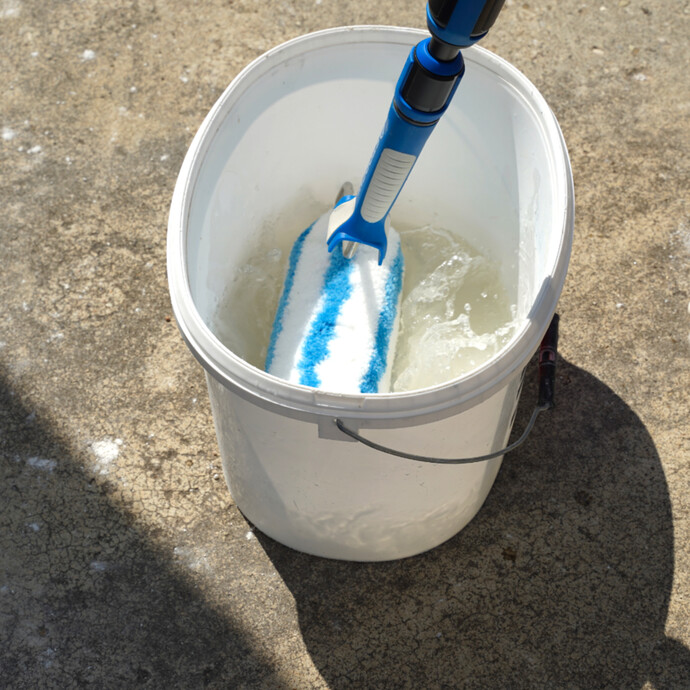 Die Farbwalze wird in einem Eimer Wasser angefeuchtet.