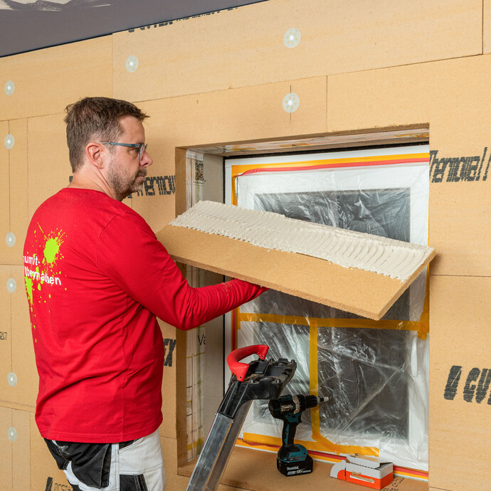Die Holzfaserdämmplatte für die Laibung im Fenstersturz ist mit Klebemörtel vorbereitet und wird vom Handwerker in den Fenstersturz geklebt. Innendämmung zum Selbermachen von Baumit.