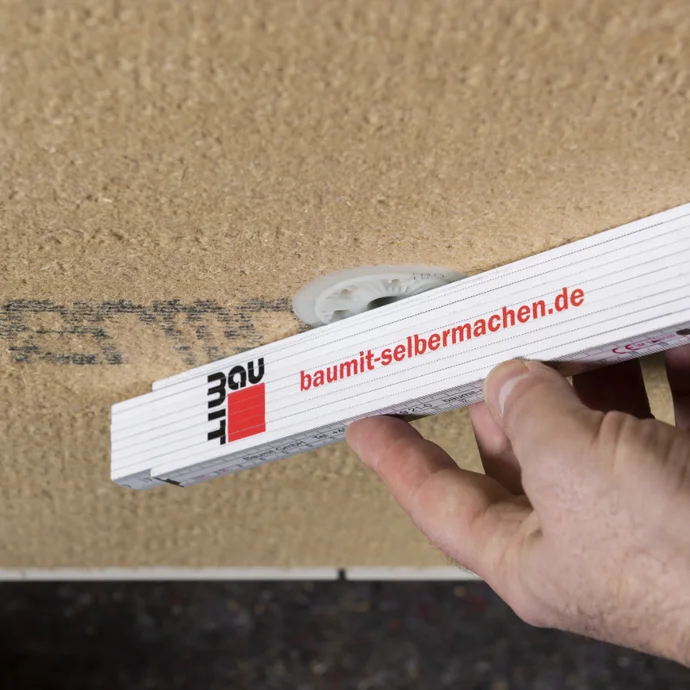 Hand hält Wasserwaage an Dämmsystem, um exakte Ausrichtung für Heimwerkerprojekt auf baumit-selbermachen.de zu prüfen.
