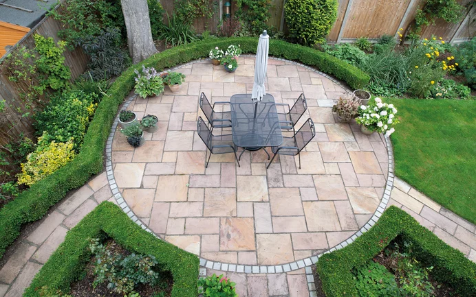 Gepflegte Terrasse mit Natursteinplatten und Sitzbereich, umgeben von Buchsbaumhecken, ideal für Heimwerkerprojekte im Garten.