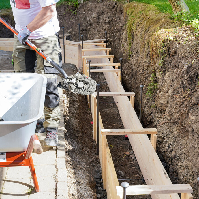 Zum Abschluss wird Kies außen seitlich an die Schalungselemente geschüttet. So kann der Beton später nicht herausquellen.