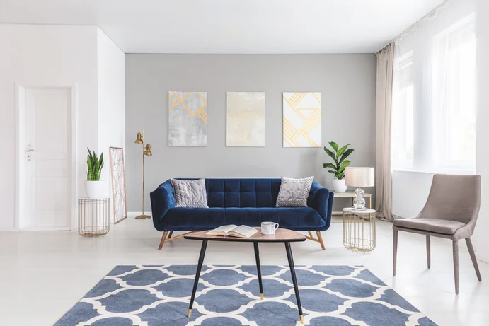 Intérieur moderne avec canapé bleu, plantes et décorations murales géométriques. Découvrez des idées de décoration pour votre intérieur.