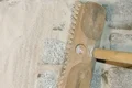 Besen entfernt Fugenmaterial von neu verlegtem Pflasterstein für eine glatte Oberfläche beim Heimwerkerprojekt.