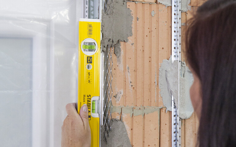 Vérification de la position d'aplomb des équerres métalliques (rail d'angle) à l'aide du niveau à bulle.