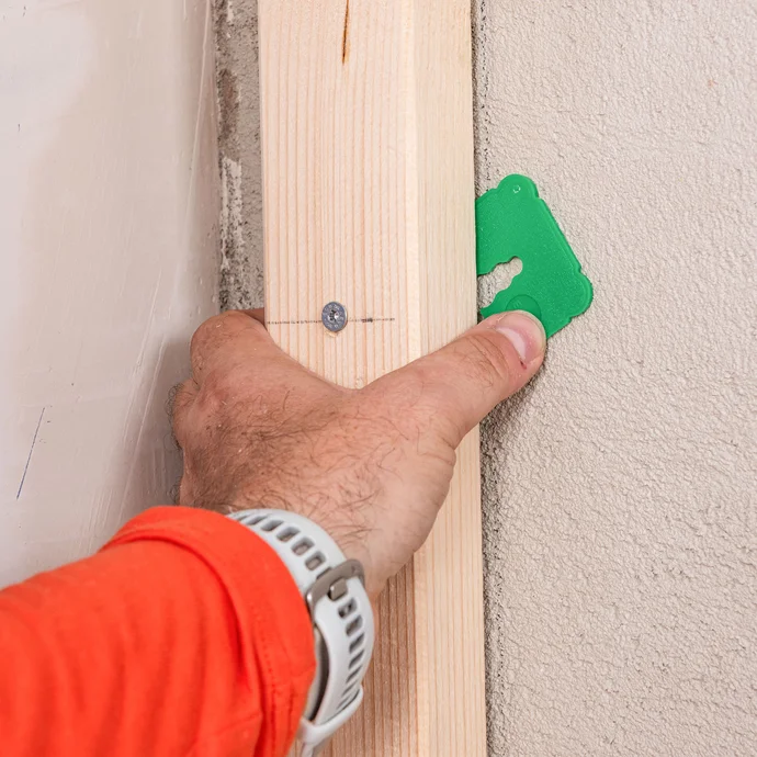 Befestigung der Tragkonstruktion aus Holz: Mit dem Baumit Ausgleichstück wird das Kantholz an der Wand verschraubt, um die Unebenheit an der Wand auszugleichen.
