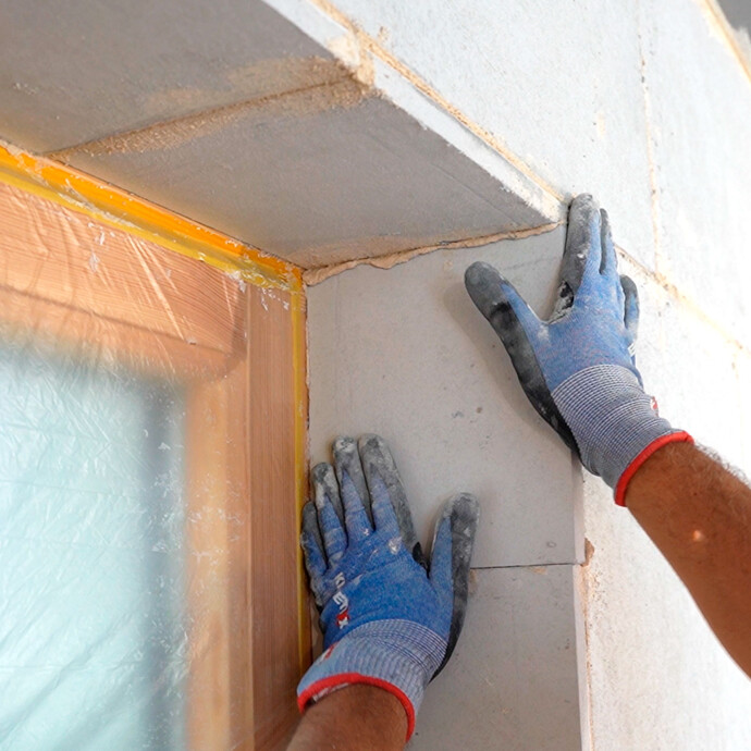 In der Fensterlaibung wird die letzte Kalziumsilikat-Laibungsplatte geklebt.