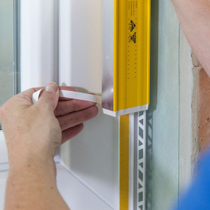 La bande de protection du ruban adhésif sur la moulure de crépi est entièrement retirée.