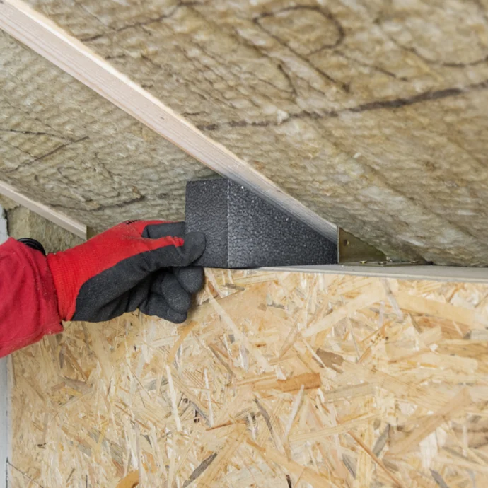 Pose d’un isolant au plafond avec lambris en bois : le bricoleur installe un bloc de mousse rigide pour améliorer l’isolation thermique.