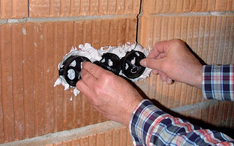 Einbau von Unterputzdosen in eine Ziegelwand für Elektroinstallationen.