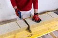 Die Baumit Mineralwolle-Dämmplatte Lamelle wird mit einer Säge zugeschnitten.