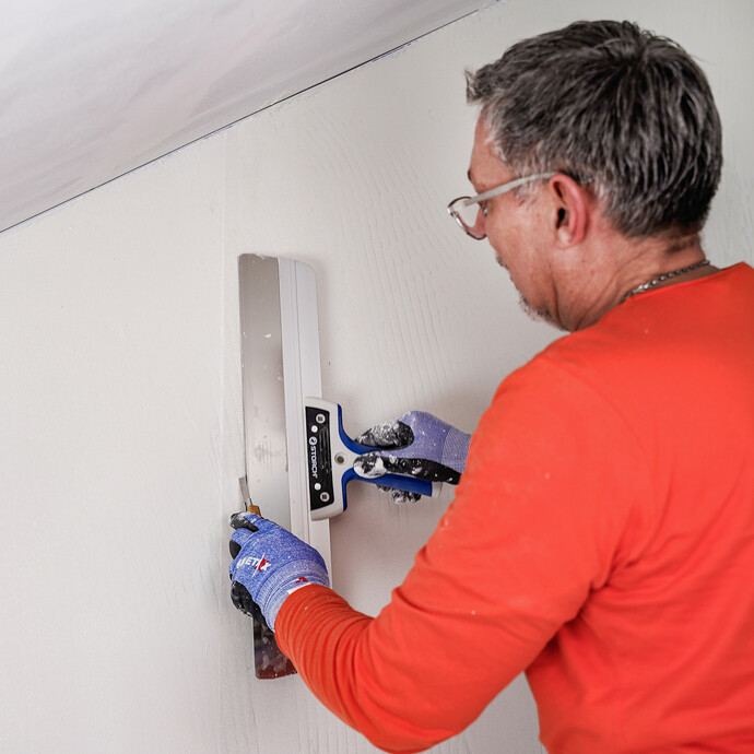 L'homme effectue une coupe à double cordon avec une spatule de surface et un cutter.