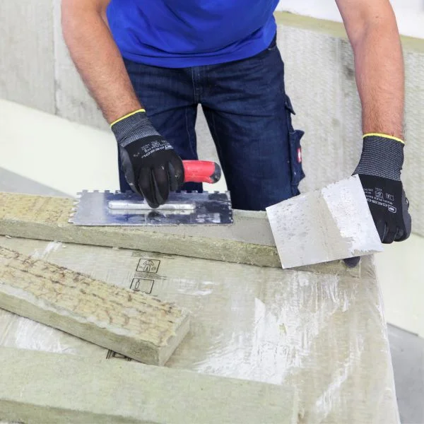 Klebespachtel auf die Rückseite der Dämmplatte aus Mineralwolle für die Fensterlaibung auftragen