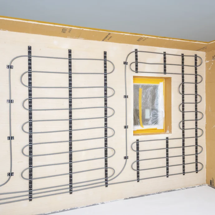 Wand mit verlegter Wandheizung vor Fenster, bereit für Putzauftrag in Heimwerkerprojekt.