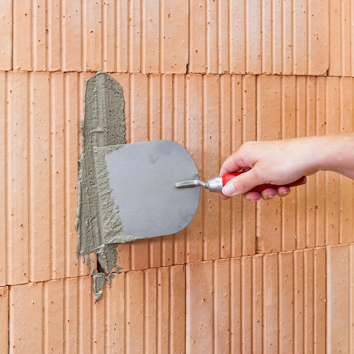 Les fissures dans la maçonnerie sont comblées avec le mortier d'enduit.
