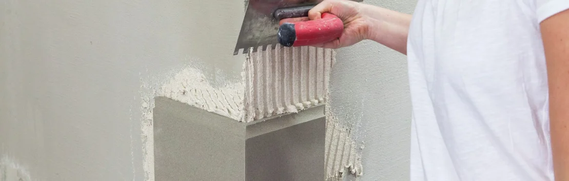 Un bricoleur applique de l'enduit &agrave; la truelle sur un mur, un produit Baumit pour des surfaces murales parfaites.