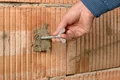 Hand füllt Riss in Mauerwerk mit Reparaturmörtel; Heimwerkerprojekt zur Ausbesserung von Wänden.