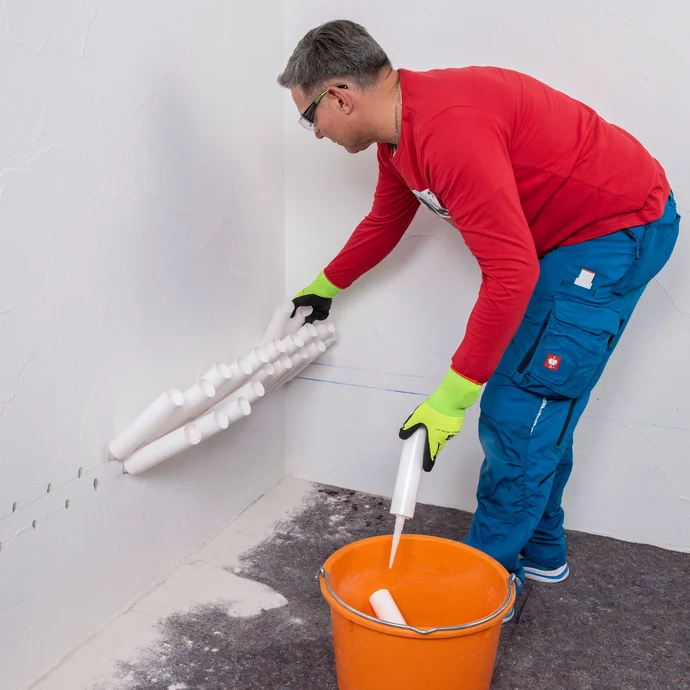 Handwerker entfernt die Injektionstrichter aus der Wand und legt sie in einen Eimer.