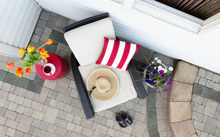Gemütlicher Outdoor-Loungesessel auf gepflasterter Terrasse mit Dekokissen und Blumenarrangement, ideal für Heimwerkerprojekte.