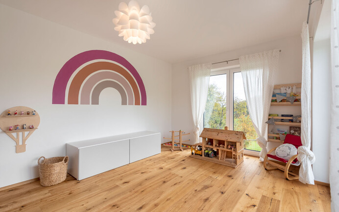 Des jouets modernes pour la chambre d'enfant, un sol en bois et l'enduit noble blanc brillant InStyle Edelweiss avec une structure d'enduit feutrée pour un climat intérieur agréable.