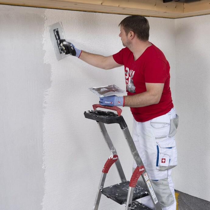 Mann strukturiert Rillenputz mit Reibebrett.