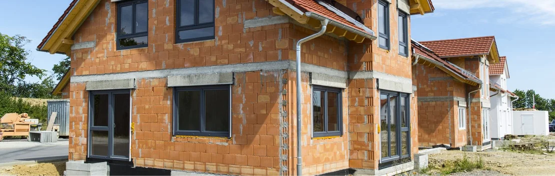 Maison neuve avec un toit en tuiles rouges et des murs en briques apparentes par temps ensoleill&eacute;, id&eacute;ale pour les projets de bricolage et les ma&icirc;tres d&rsquo;ouvrage.