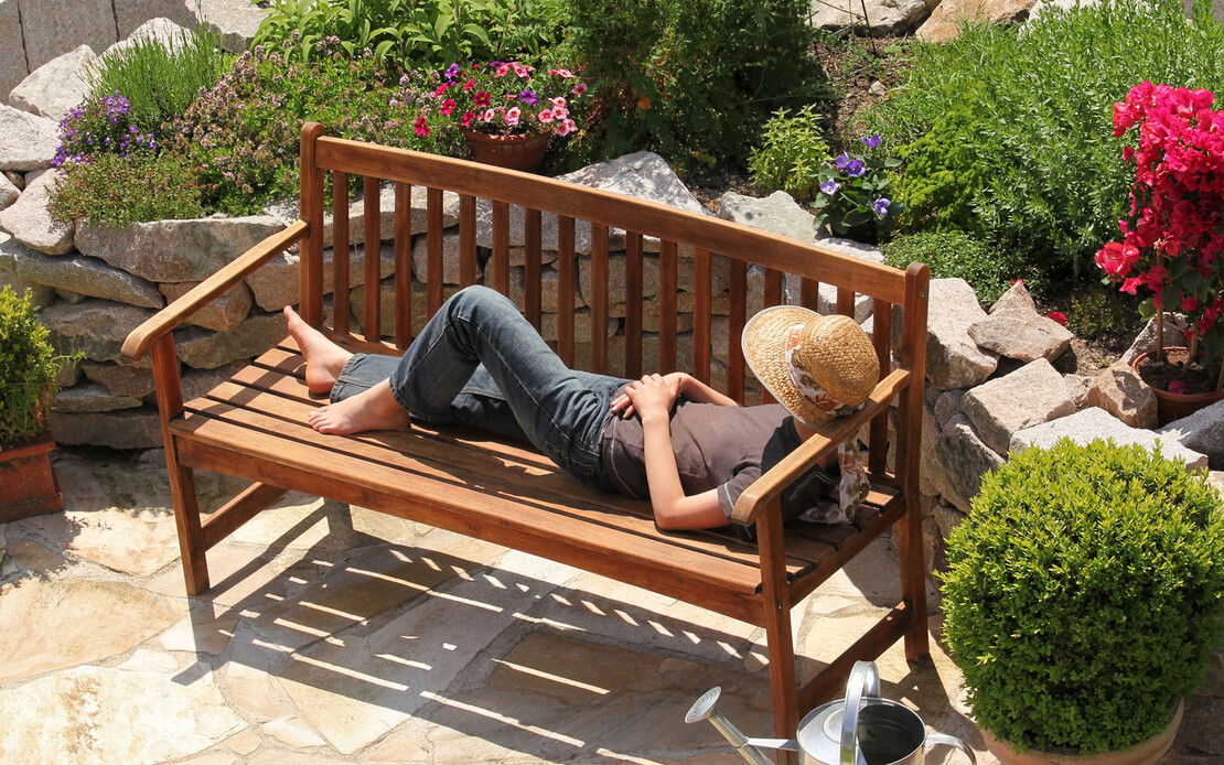 Ein Frau entspannt in ihrem blühenden Garten.