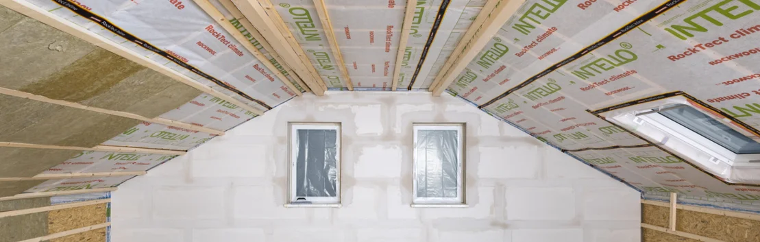 Dachbodenausbau mit D&auml;mmung und rigidem Schaumstoff, vorbereitet f&uuml;r Verkleidung, inklusive Dachfenster f&uuml;r verbesserten Lichteinfall.