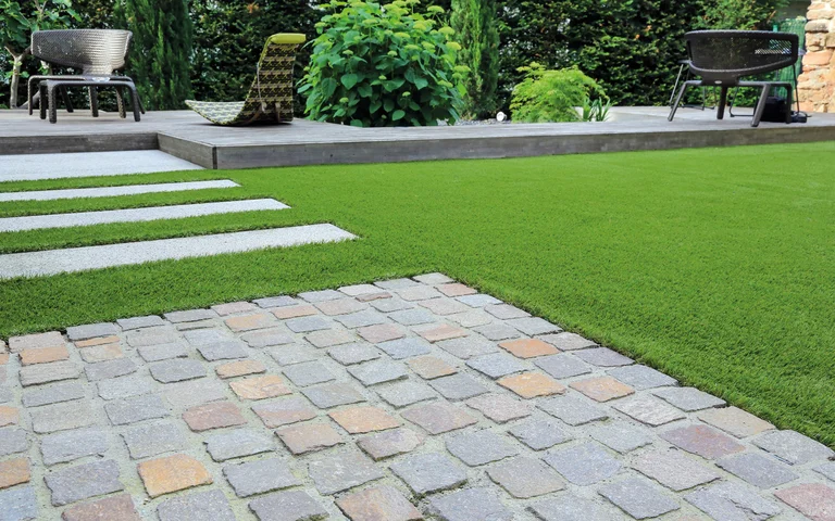 Gepflegter Garten mit Steinweg und Kunstrasen, ideal für DIY-Projekte zur Verschönerung des Außenbereichs.
