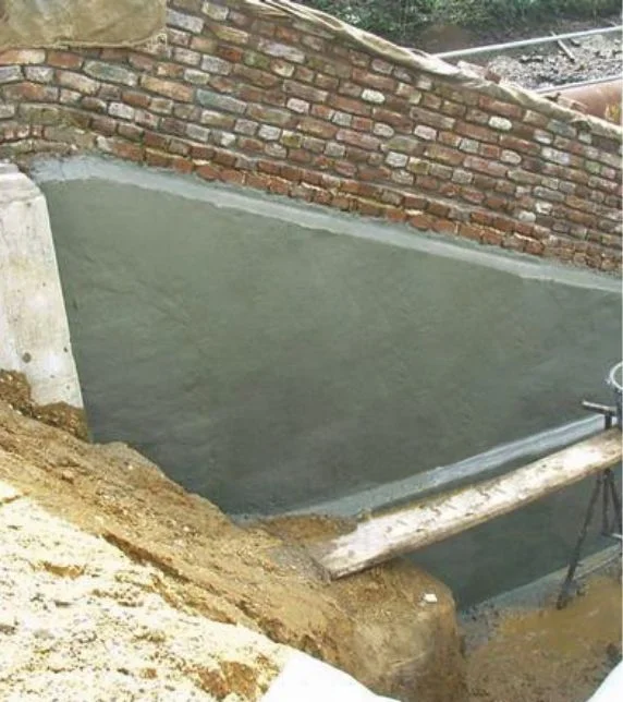 Rénovation de maçonnerie avec un enduit neuf sur un ancien mur de briques pour une protection efficace et un aspect amélioré.