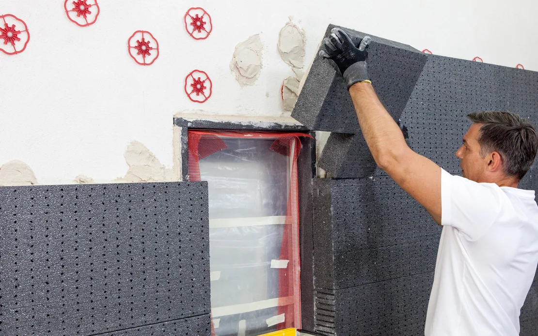 Un bricoleur pose des panneaux isolants sur une fa&ccedil;ade afin d&rsquo;am&eacute;liorer l&rsquo;efficacit&eacute; &eacute;nerg&eacute;tique. Instructions &eacute;tape par &eacute;tape sur le site web de Baumit.