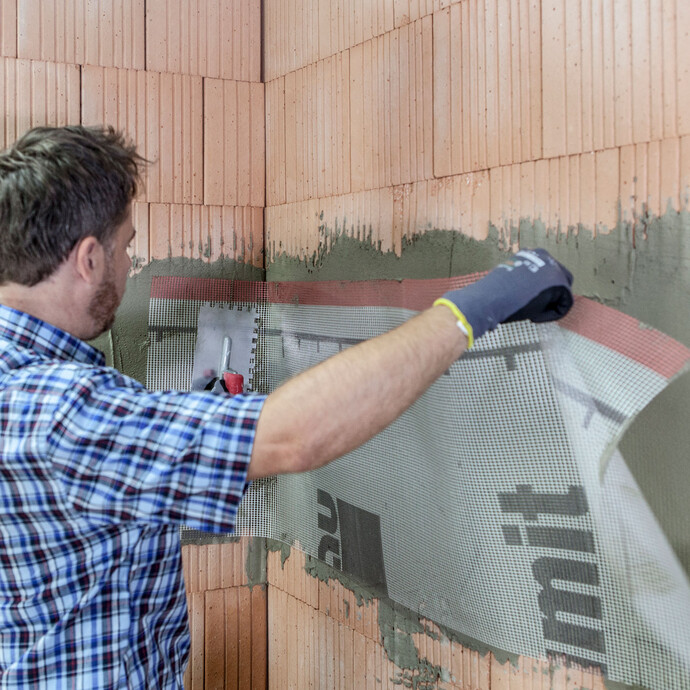 In der Innenecke setzt der Heimwerker eine weitere Gewebebahn überlappend ein und verspachtelt das Gewebe.