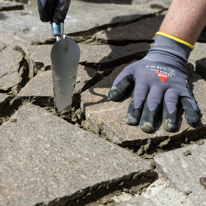 Direkt nach dem Verkleben wird überschüssiger Steinkleber aus den Fugen mit einer Fugenkelle entfernt.