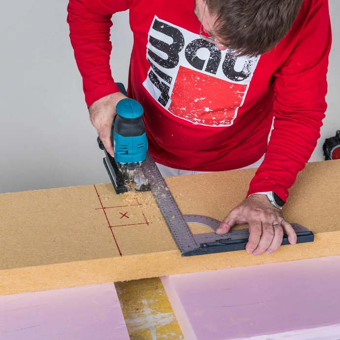 Heimwerker schneidet Aussparung für Steckdose in Baumit Holzfaserdämmplatte mit Stichsäge und Winkel zu – Dämmplatte passgenau für Innendämmungsdose zuschneiden, Baumit Selbermachen Anleitung.