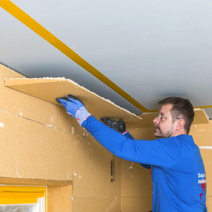 Heimwerker montiert Trockenbauplatte an Decke; Schritt-für-Schritt Anleitung auf Baumit-Selbermachen für DIY-Projekte.