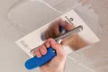 Hand trägt mit Glättkelle Spachtelmasse an Decke auf, Nahaufnahme im DIY-Kontext für Heimwerkerprojekte.