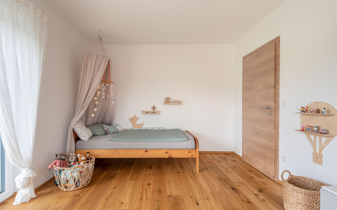 Chambre d'enfant moderne avec lit et jouets, sol en bois et enduit noble blanc brillant InStyle Edelweiss avec structure d'enduit feutrée pour un climat ambiant agréable.