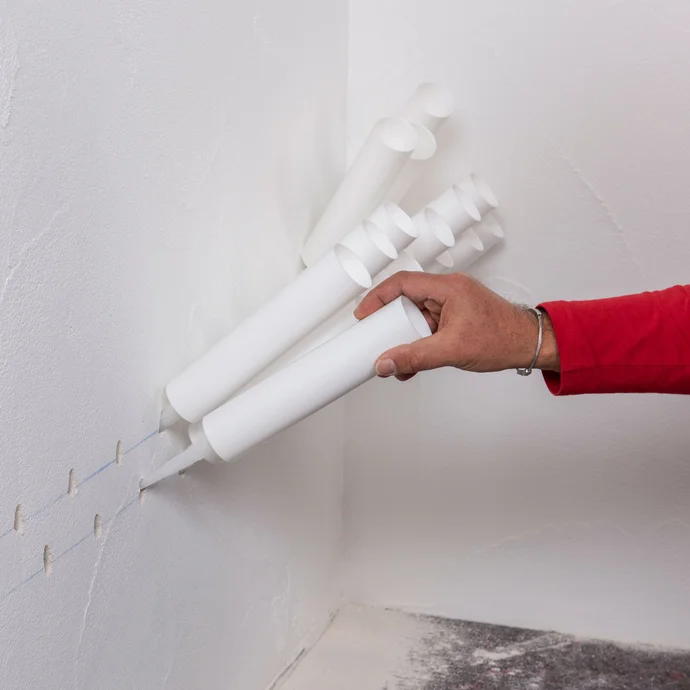 Handwerker setzt die vorbereiteten Injektionstrichter in die zuvor gebohrten Löcher ein.