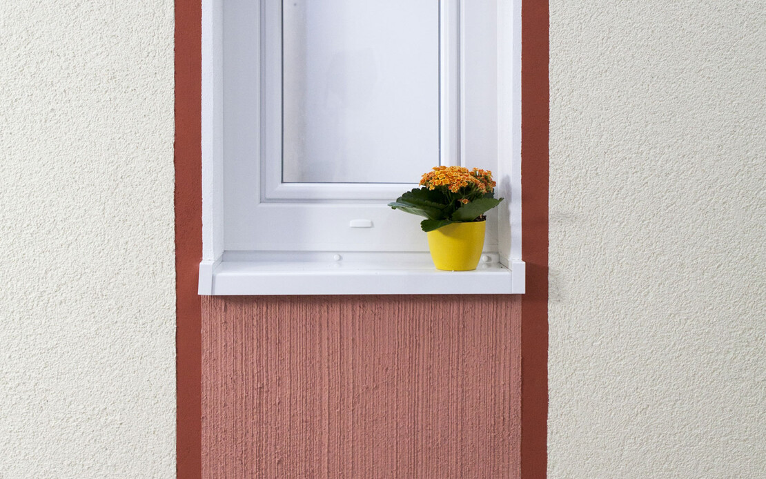 Fenster mit Blumentopf auf dem wei&szlig;en Fensterbrett. Es sind zwei rote Streifen links und rechts die unterhalb des Fensters mit hellroter Farbe ausgef&uuml;llt sind.