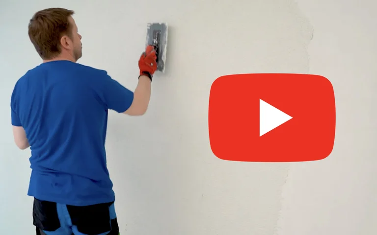 Person verputzt Innenwand mit Kelle, symbolisiert DIY-Anleitung.