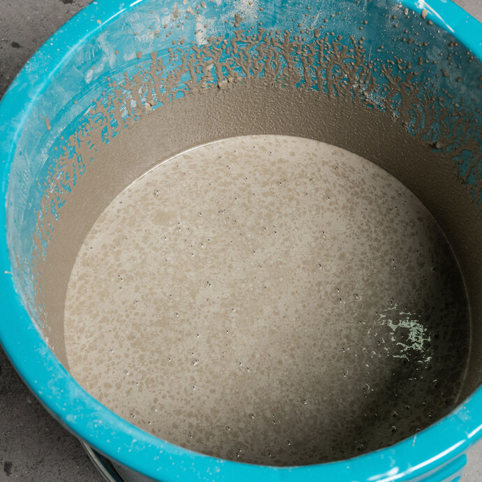 Photo en gros plan : Seau bleu avec masse d'égalisation mélangée - respecter le temps de maturation : La masse d'égalisation reste quelques minutes au repos avant d'être à nouveau mélangée.