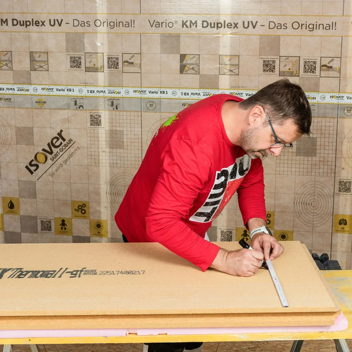 Der Heimwerker zeichnet die Position der Verteilerdose auf der Holzfaserdämmplatter Themowall gf ein. Innendämmung mit Holztragkonstruktion bauen. Schritt für Schritt erklärt.