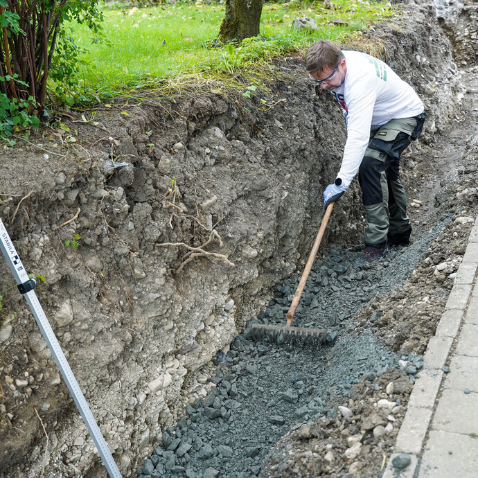 Verteile den Frostschutzschotter gleichmäßig mit einer Harke oder einem Rechen.