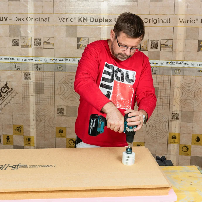 Der Baumit Handwerker sägt die markierte Position der Gerätedose mit Hilfe einer Lochsäge aus der Holzfaserdämmplatte aus. Verteilerdose in eine Innendämmung einbauen zum Selbermachen.