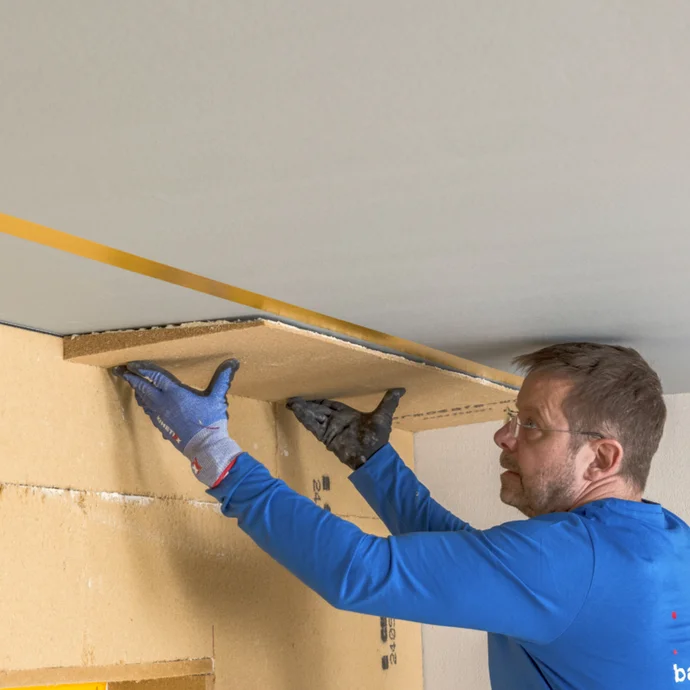 Mann montiert Trockenbauplatte für Decke mit Baumit Heimwerker-Guide.