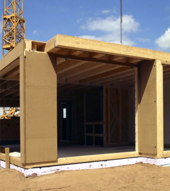 Construction bois durable : charpente d’une maison moderne sur un chantier sous un ciel bleu.