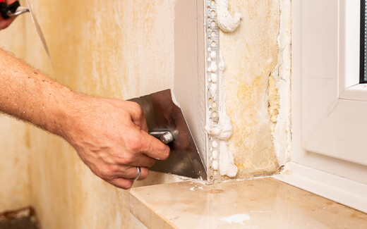 Eckprofil beim Spachteln von Wänden mit Spachtelmasse an den Fenstern setzen