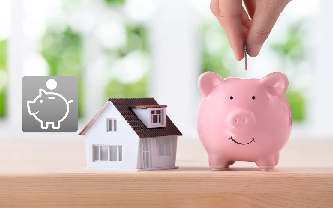 Conseils pour &eacute;conomiser lors de travaux de r&eacute;novation : maquette de maison et tirelire pos&eacute;es sur une table en bois, symbole de projets de construction rentables.