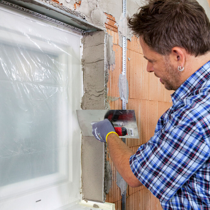 Person glättet Kalkzementputz mit einer Glättkelle. 