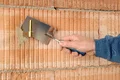 Hand verputzt Ziegelmauer mit Glättkelle, Vorbereitung für neue Putzschicht im Renovierungsprojekt.